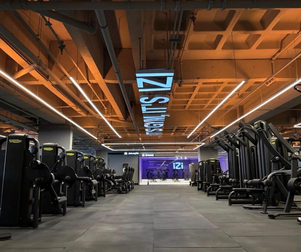 Interior da academia IZI com pé-direito alto e iluminação
