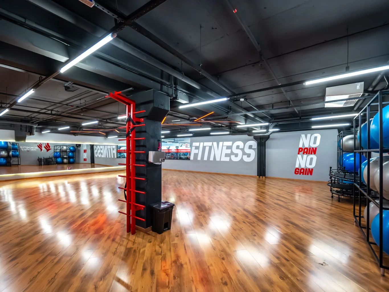 Sala de ginástica com piso de madeira e espelhos